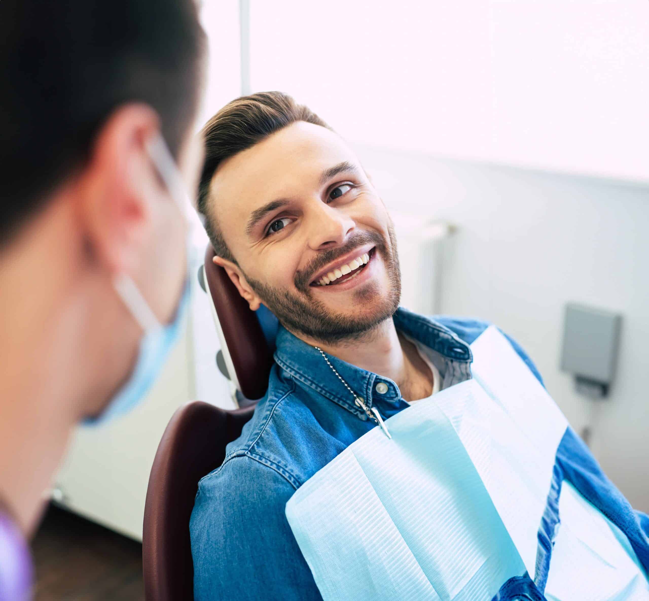 Stylish guy in a jean jacket smiling up at his orthodontist at an orthodontists appointment