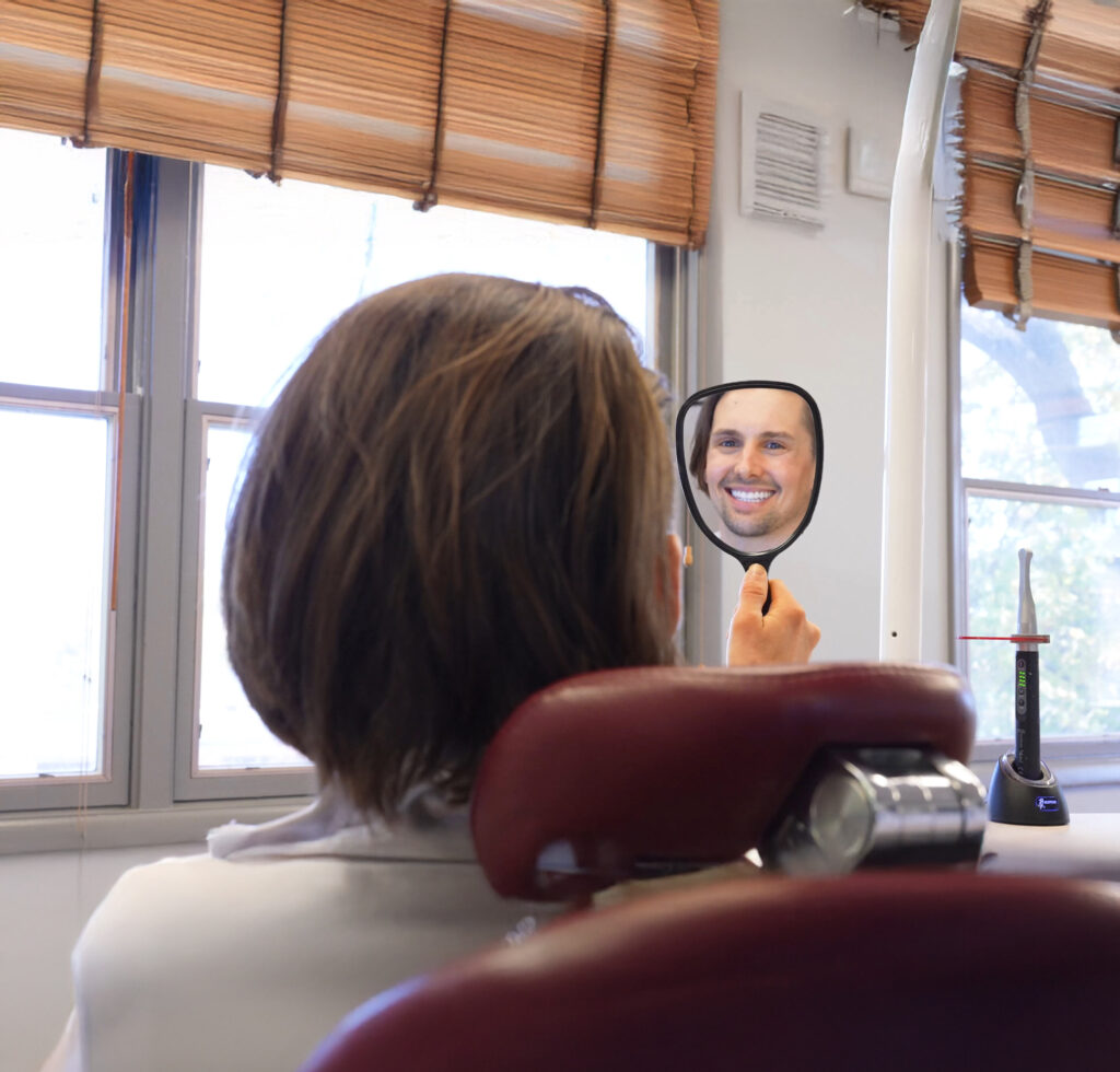 Happy adult orthodontic patient using a handheld mirror to admire his new smile