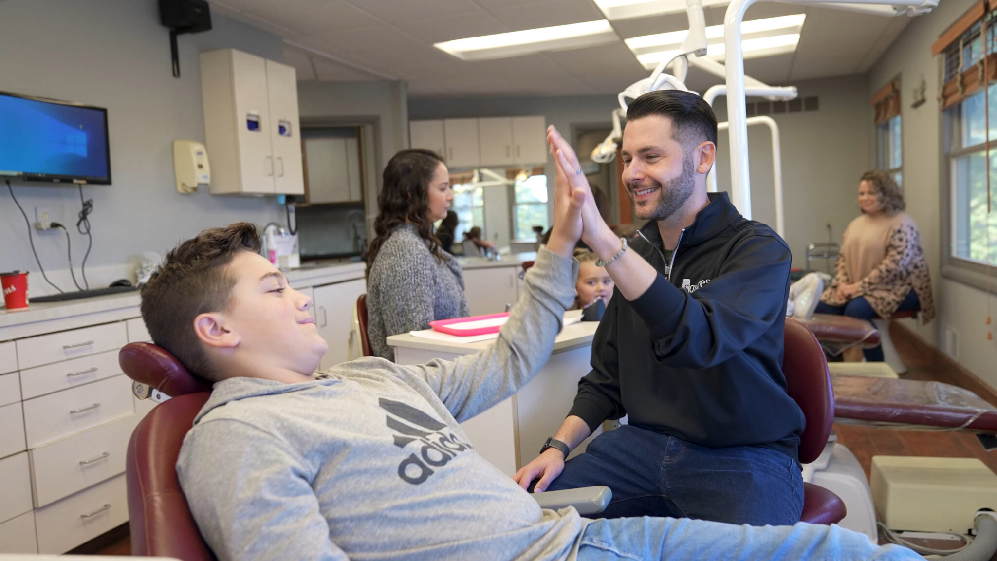 Dr. Squires giving a teen patient a high 5 after finishing with their braces appointment (Empty Alt-attribute)