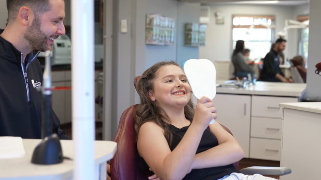 Young patient admiring her new smile after completing her treatment
