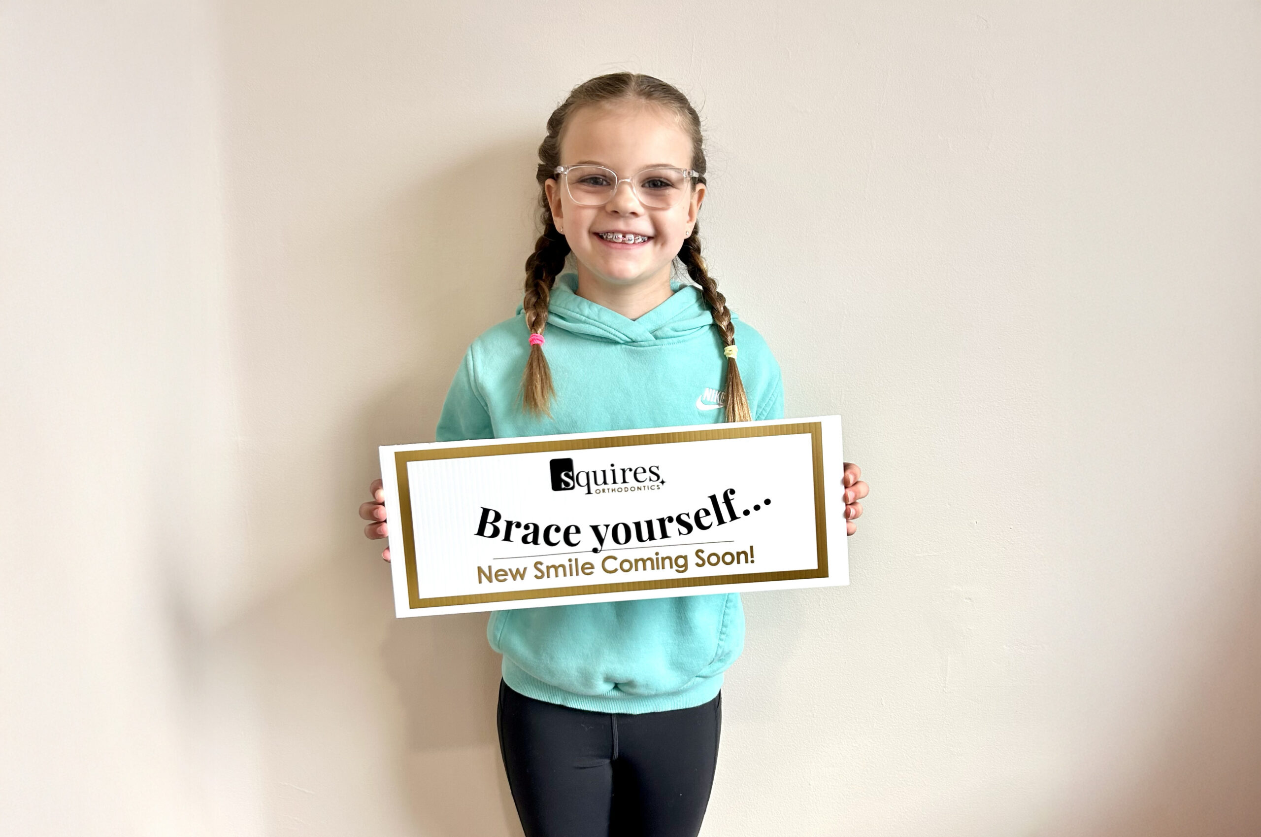 Squires patient holding a sign showing that her smile is in progress