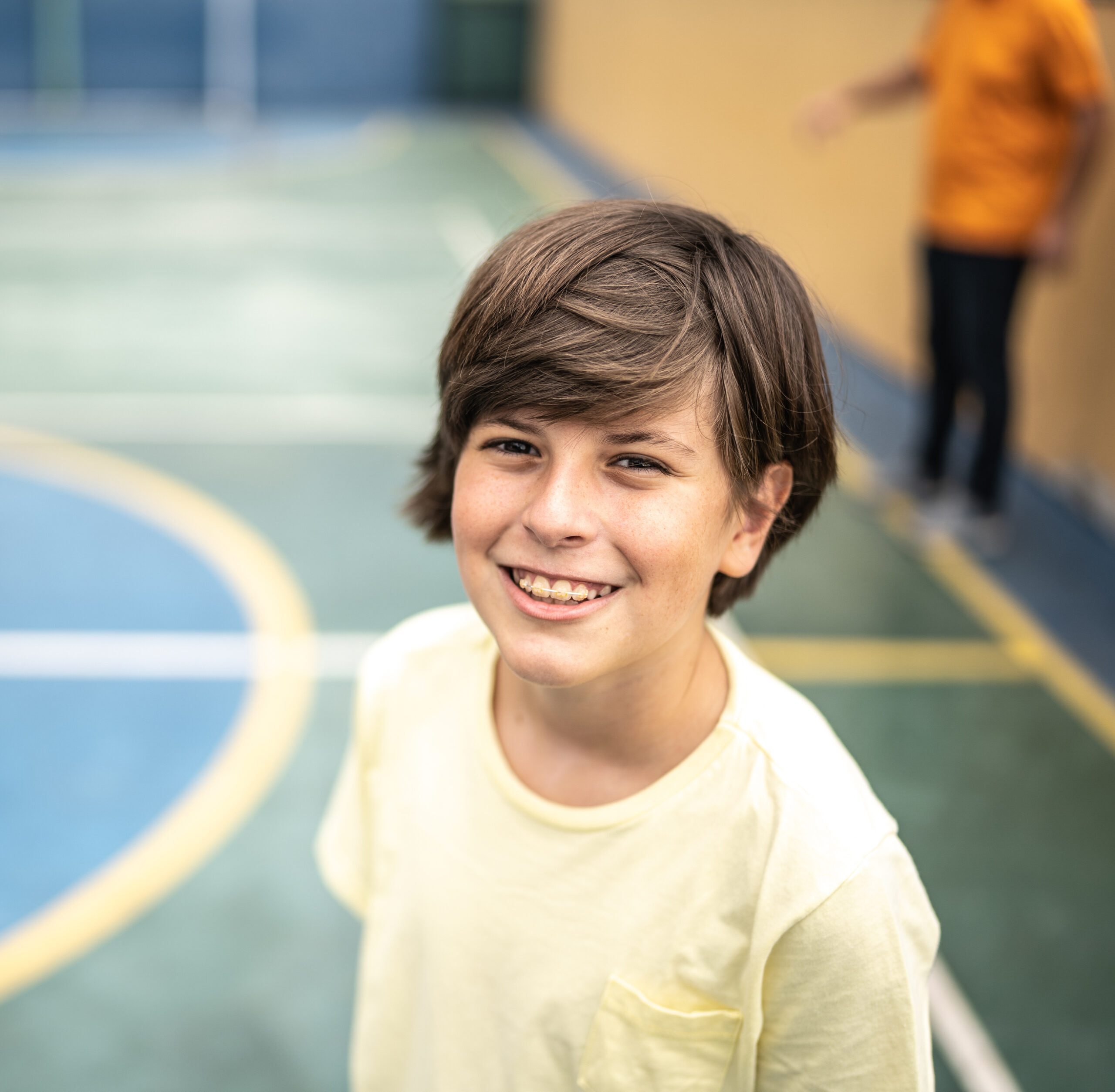 Portrait of a boy with braces at a basketball court