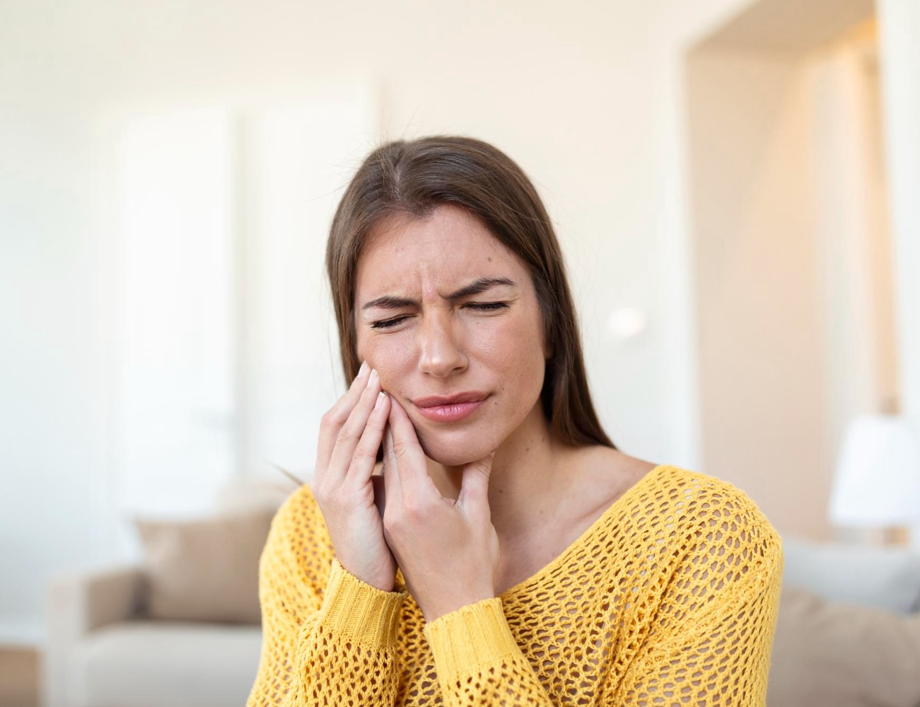 Tooth pain and dentistry beautiful young woman suffering from terrible strong teeth pain touching cheek with hand female feeling painful toothache